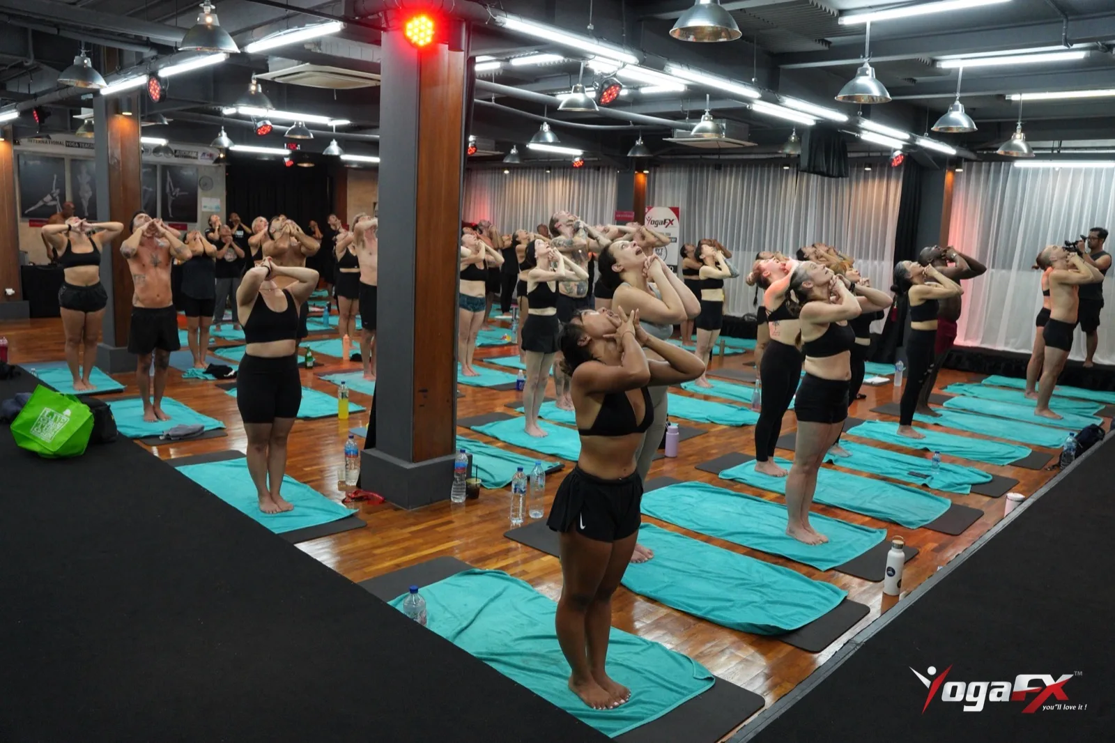 Full studio of students doing the Standing Deep Breathing exercise at the start of a 26 and 2 class