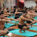 A row of men holding Awkward Pose together in the heated room at the YogaFX studio, sweating through the standing series