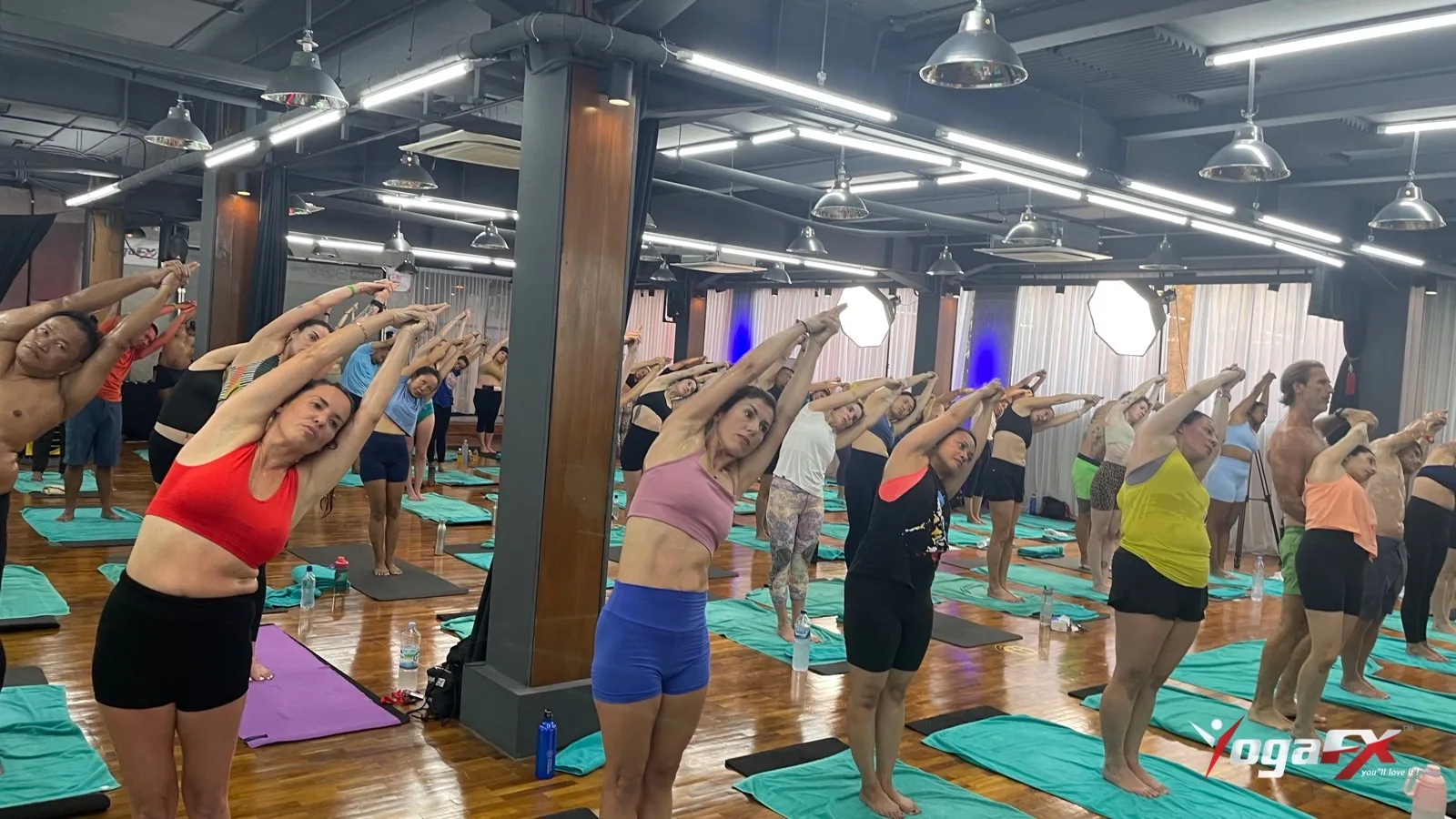 Students of different ages in the Half Moon side bend during a hot 26 and 2 class in Bali